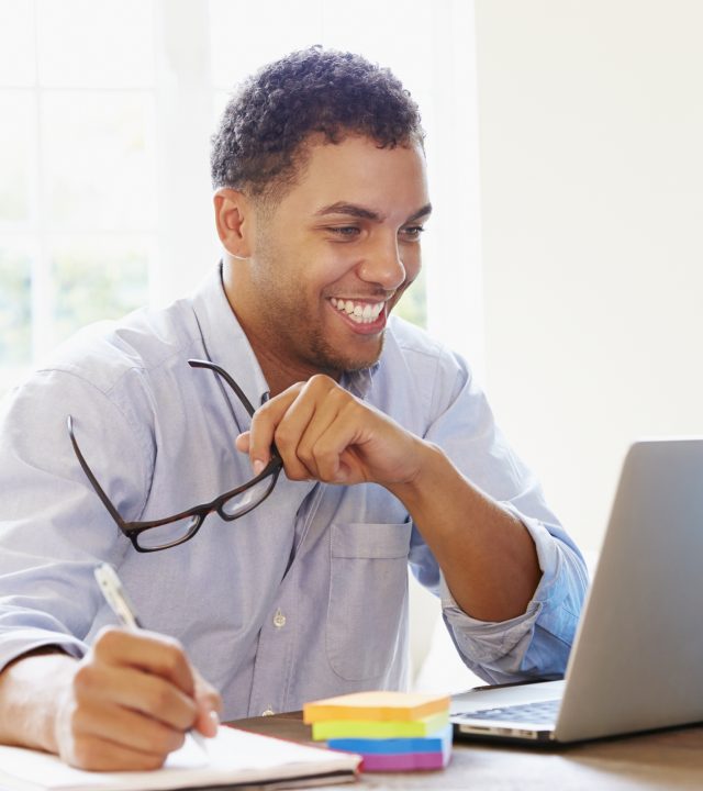 Businessman Working In Office At Home Looking At Laptop Smiling